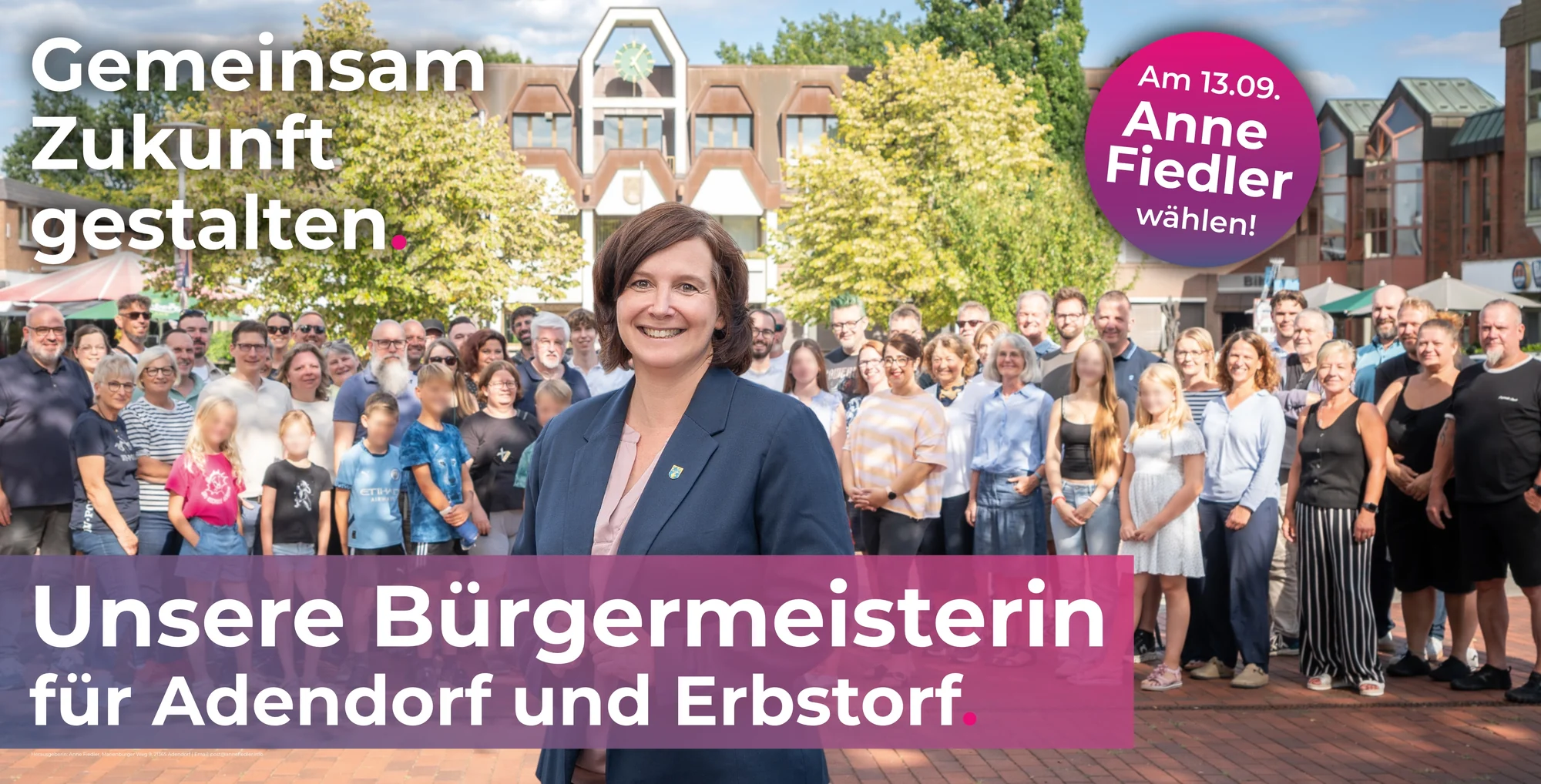 Bauzaunbanner: Anne Fiedler mit vielen Menschen aus Adendorf und Erbstorf vor dem Rathaus, Text „Gemeinsam Zukunft gestalten. Unsere Bürgermeisterin für Adendorf und Erbstorf“
